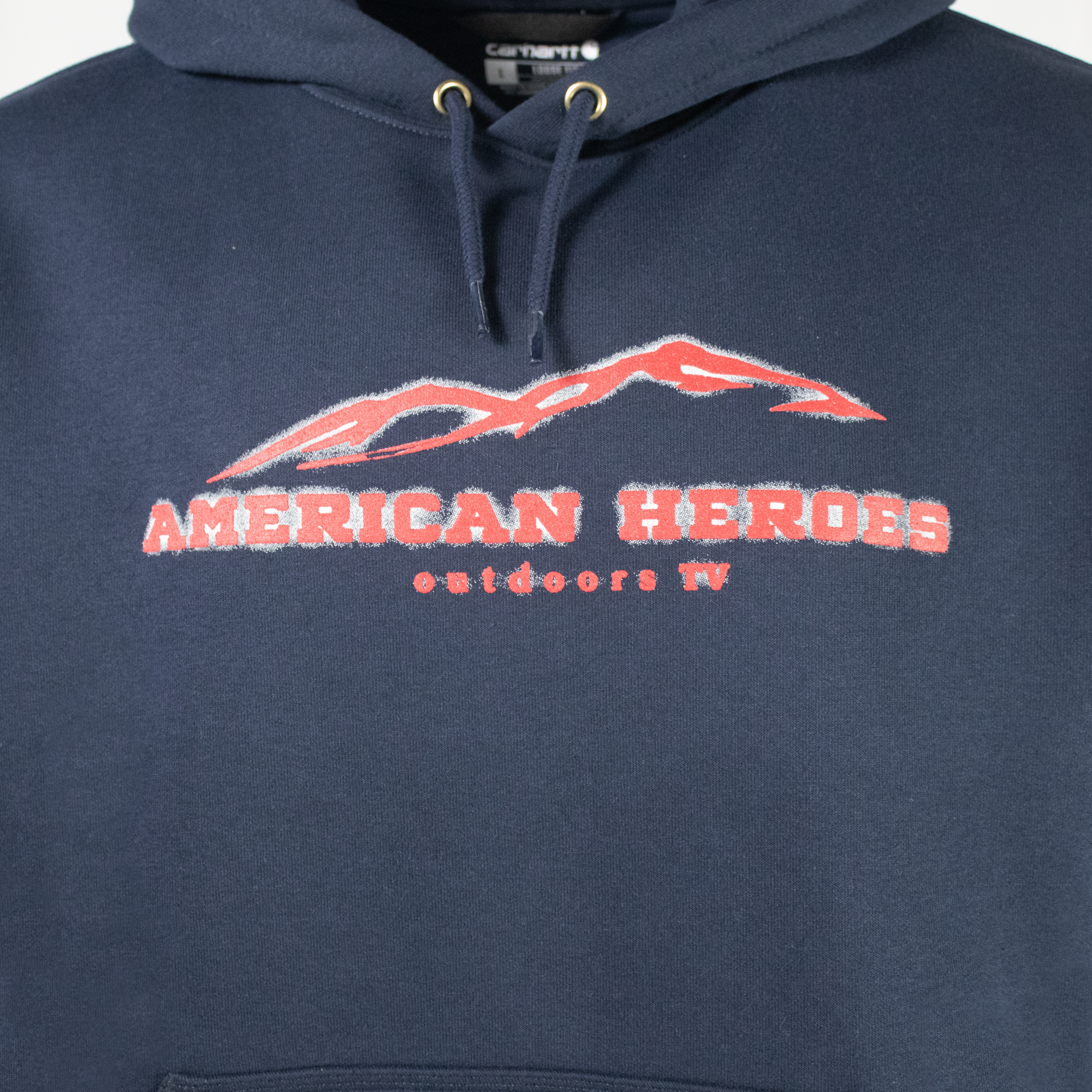 Close up of a navy blue hoodie with a red american heroes logo on the chest.